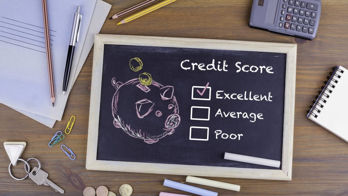 Excellent Credit Score concept. Chalkboard on wooden office desk with checklist in and piggy bank.