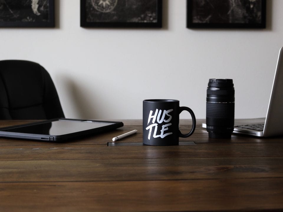 hustle mug sitting on a table with work supplies
