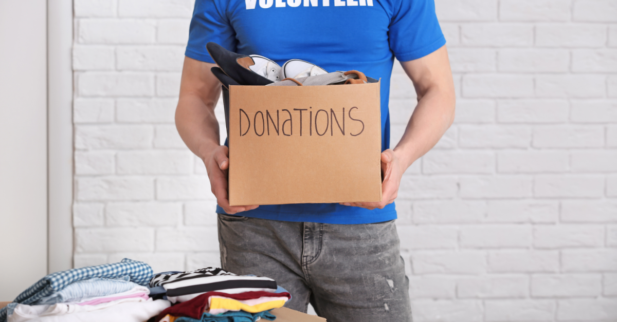 person in a blue t-shirt holding a cardboard box that reads donations