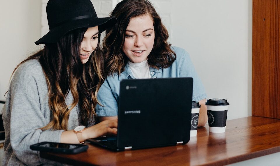 two young women using laptop in a coffee shop.
