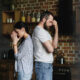 side view of young depressed couple standing back to back after quarrel at home