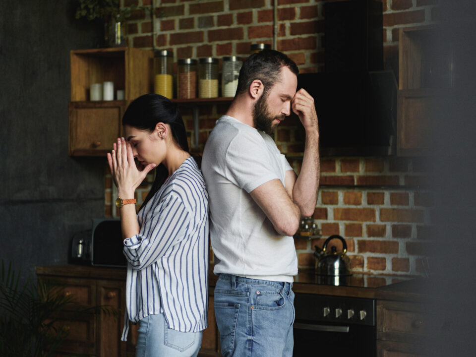 side view of young depressed couple standing back to back after quarrel at home