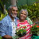 Portrait of smiling senior couple standing together while holding plants in backyard