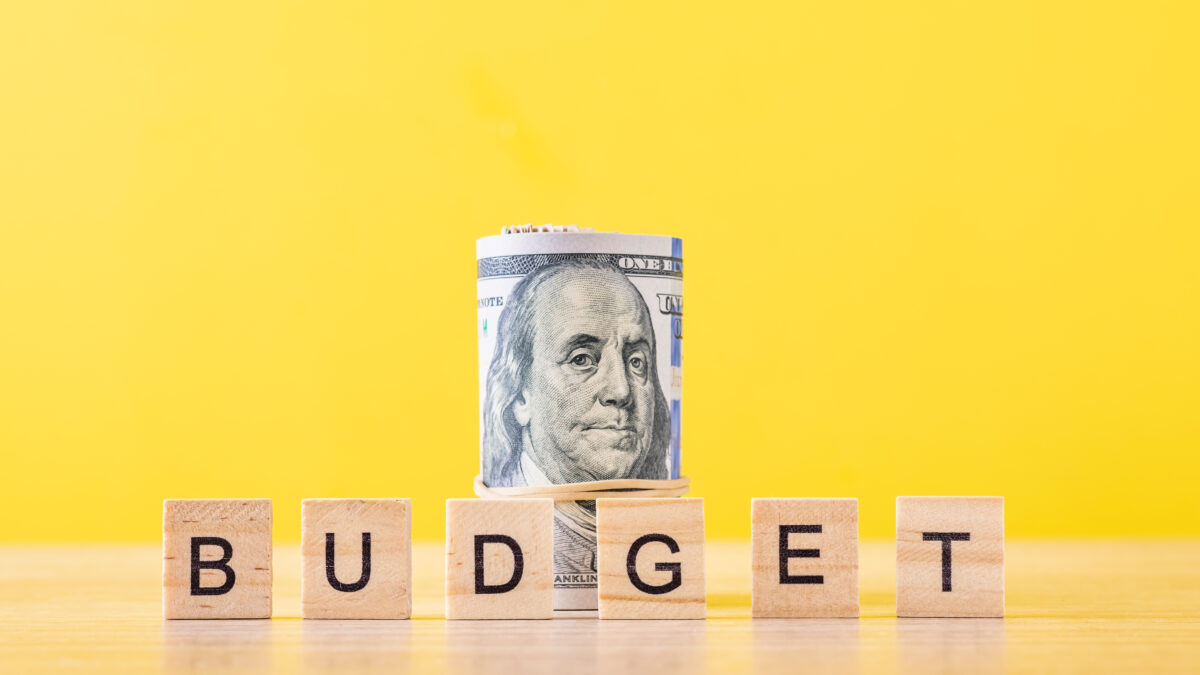 Rolled up dollar bills and word budget on yellow background. Finance accounting concept