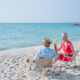Senior couple relaxing and drink orange juice at tropical beach., Healthy seniors lifestyle concept.