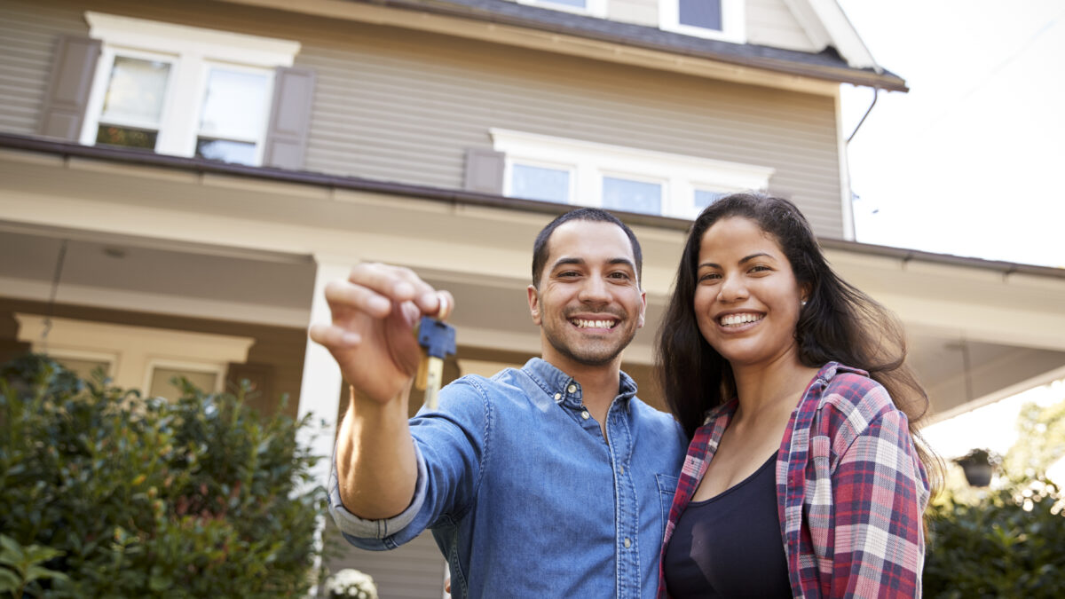 Portrait Of Couple Holding Keys To New Home On Moving In Day