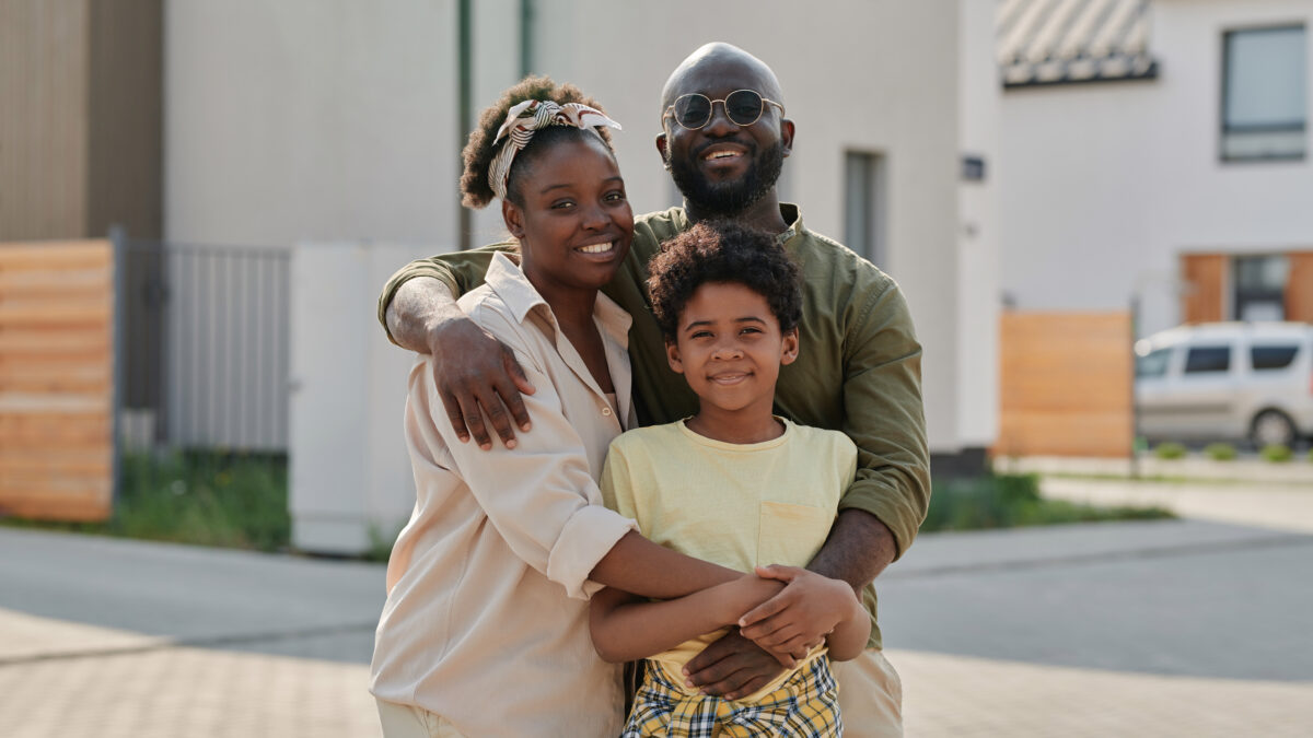 Portrait of African American family embracing and smiling at camera while walking outdoors