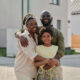 Portrait of African American family embracing and smiling at camera while walking outdoors