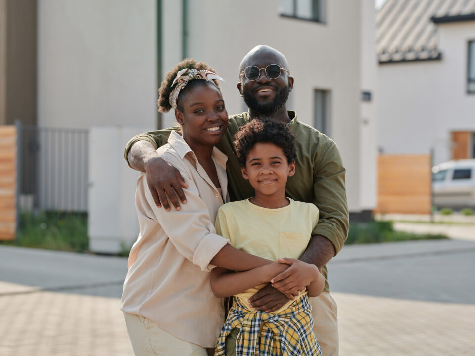 Portrait of African American family embracing and smiling at camera while walking outdoors