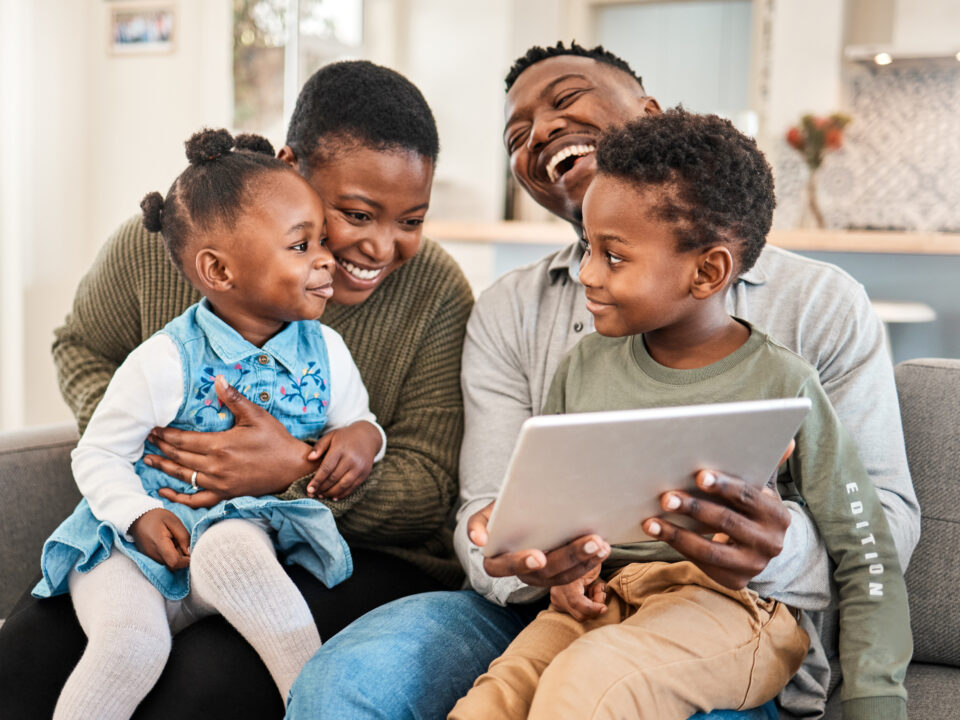 Shot of a happy young family using a digital tablet on the sofa at home.