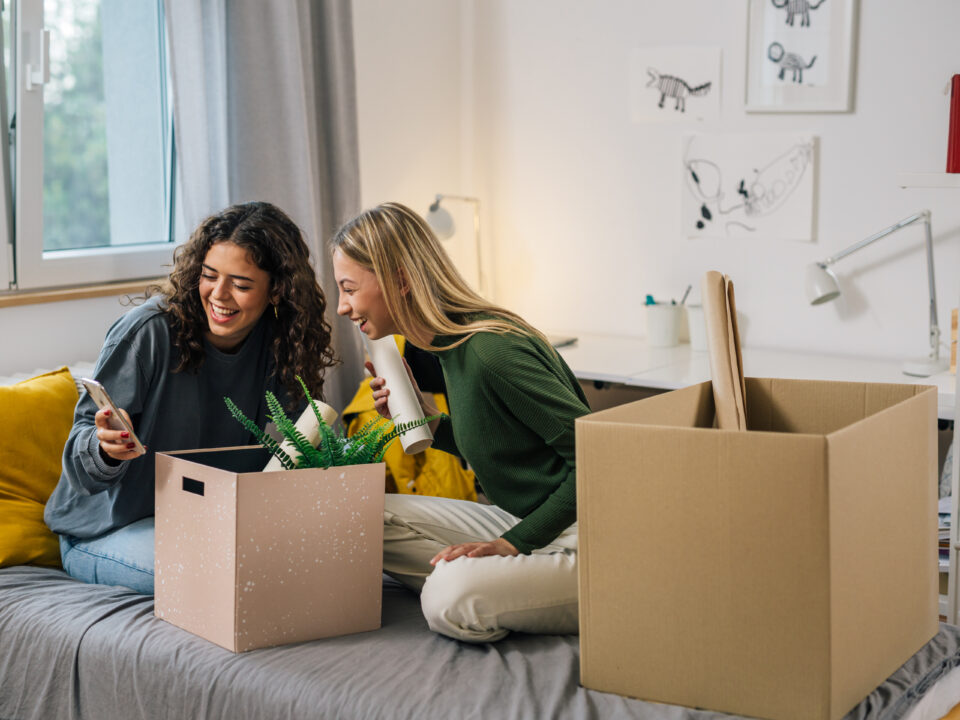 college female teenagers sits on bed and using mobile phone dorm