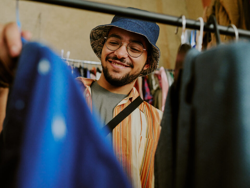 Smiling Man Shopping for Clothing in Thrift Store