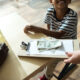 cropped shot of waiter holding bill and money while father with son sitting in cafe