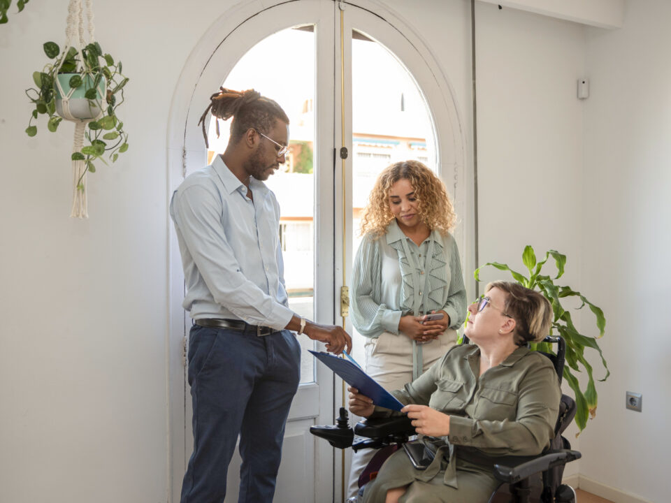 Couple caring for a disabled woman in wheelchair.